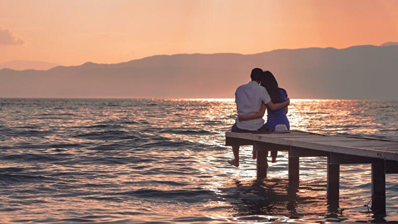 魚座のB型男性の恋愛傾向を表し女性と肩を抱き寄せ合って夕日を眺める姿